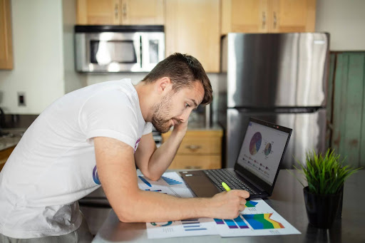 A man checking the laptop with the graphs for marketing loss and profit.